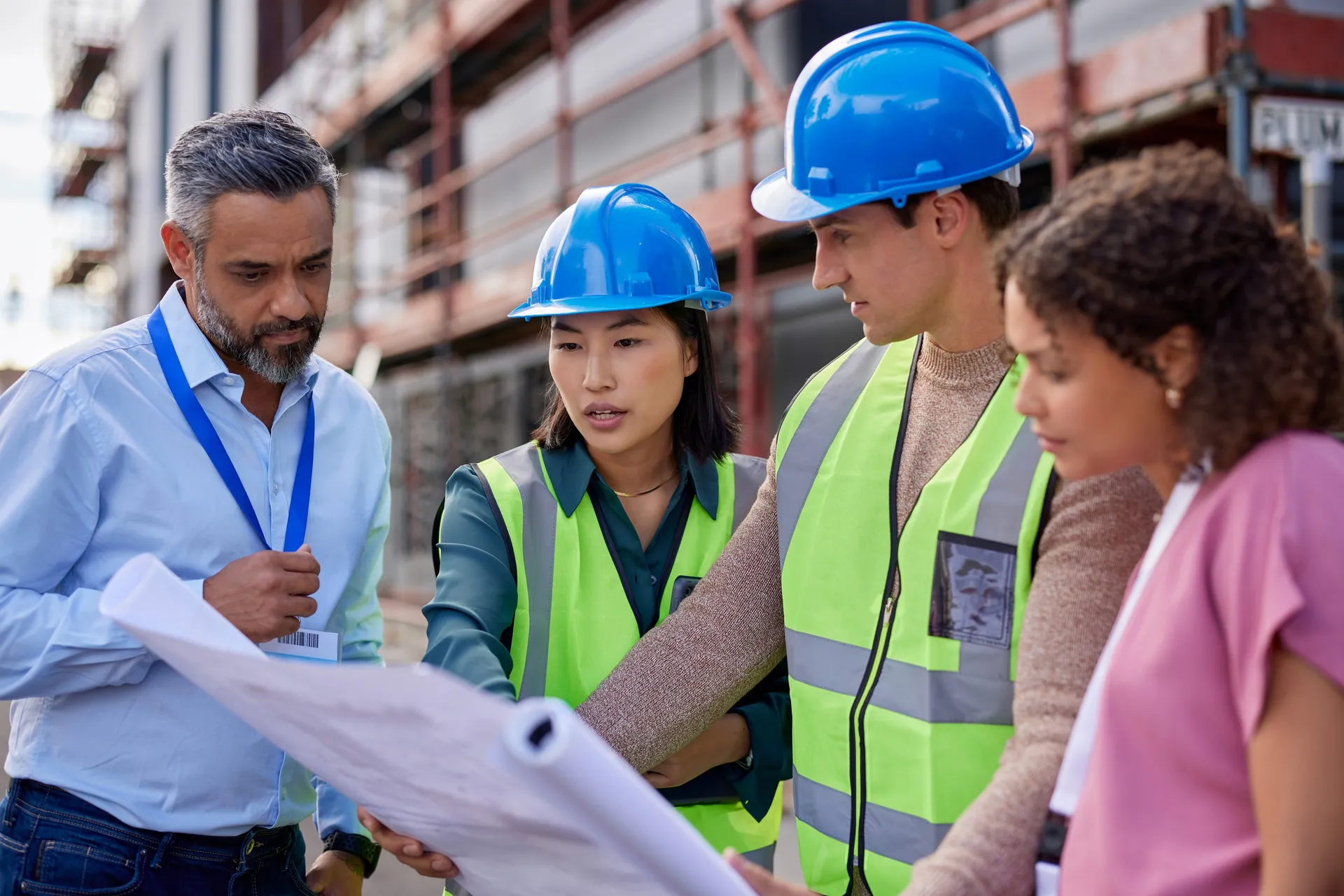 Contractors in hard hats reviewing plans together on a job site